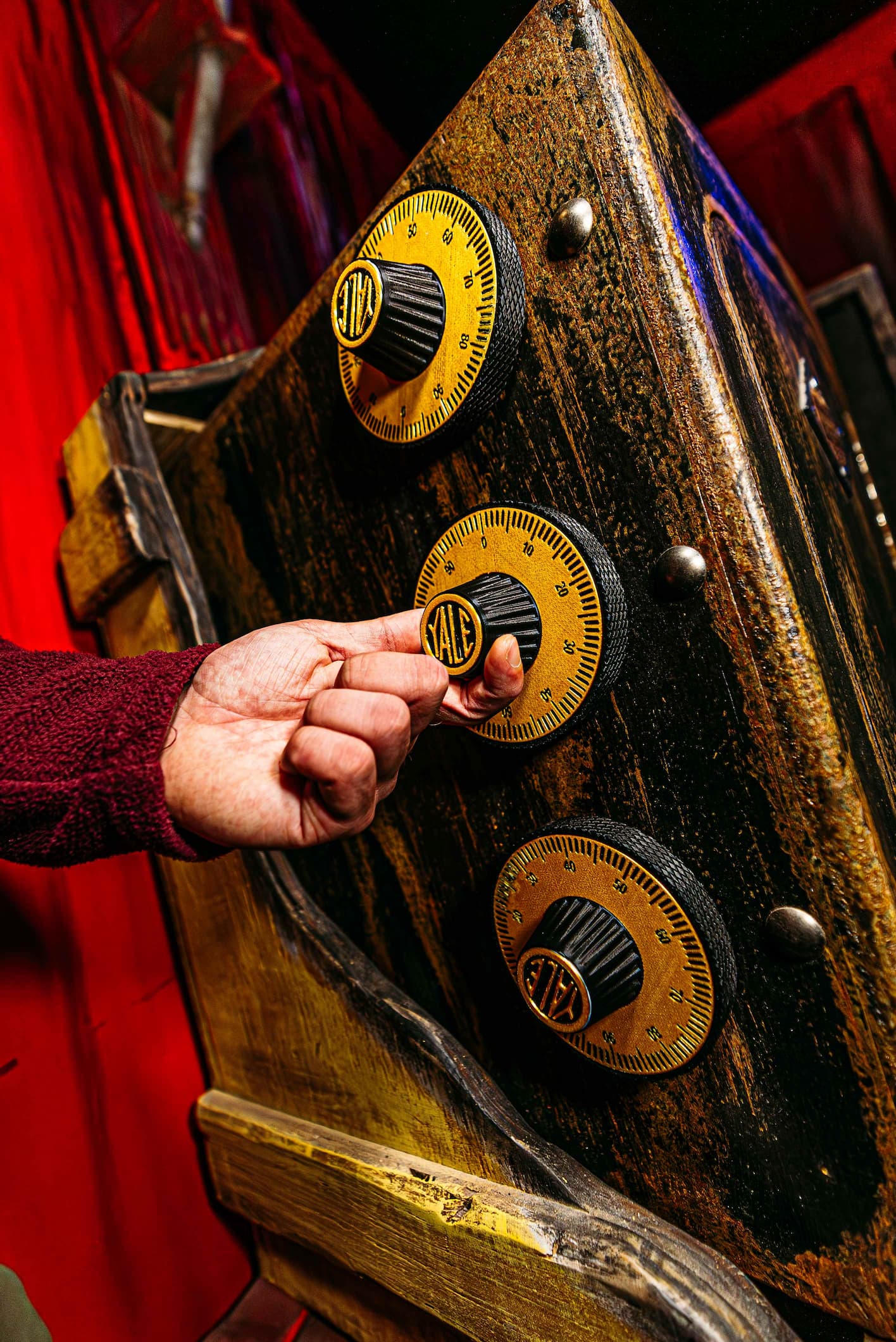 A person's hand turning the dial of an antique combination lock on a safe.